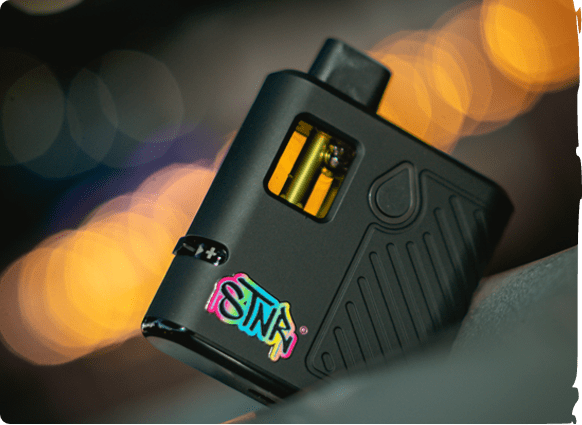 A black vaporizer with colorful STNR Creations branding rests on a blurred surface.